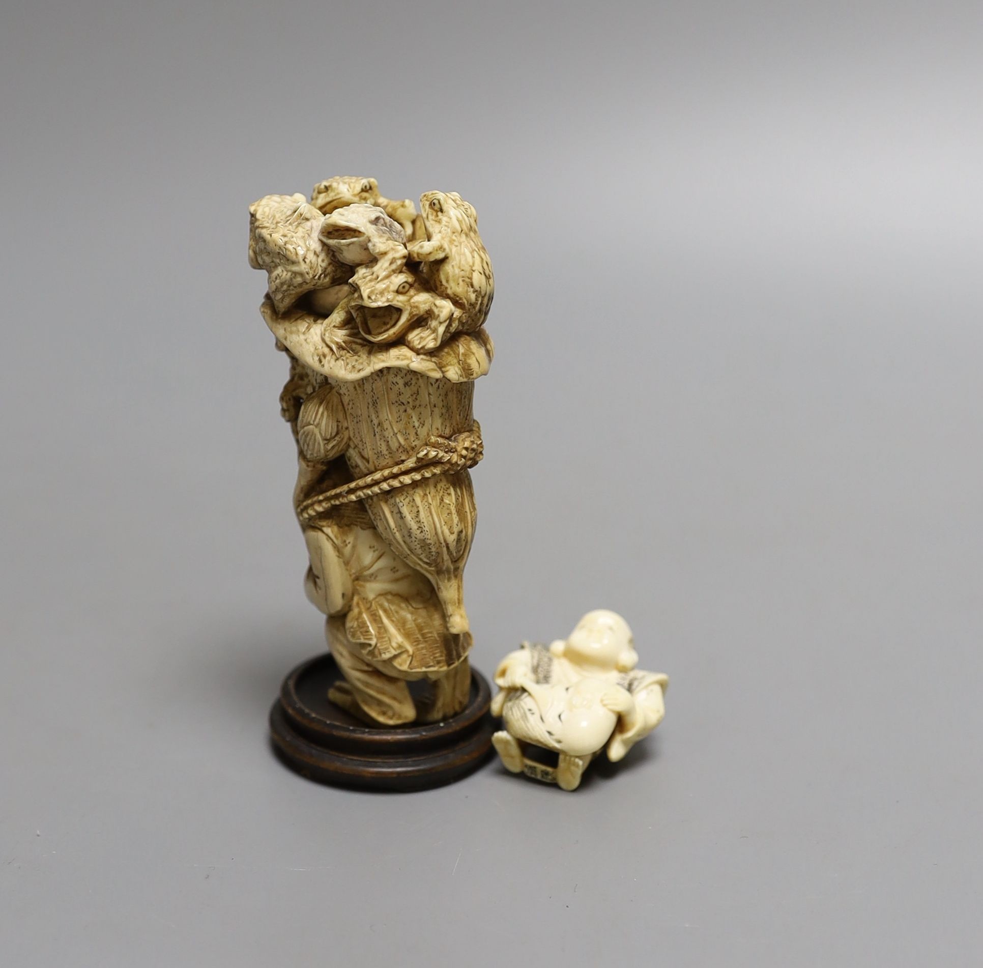 A Japanese ivory okimono of a monkey carrying a lotus leaf containing toads, on its back and an Ivory Netsuke of a mask maker, both Meiji period - tallest 9.5cm high